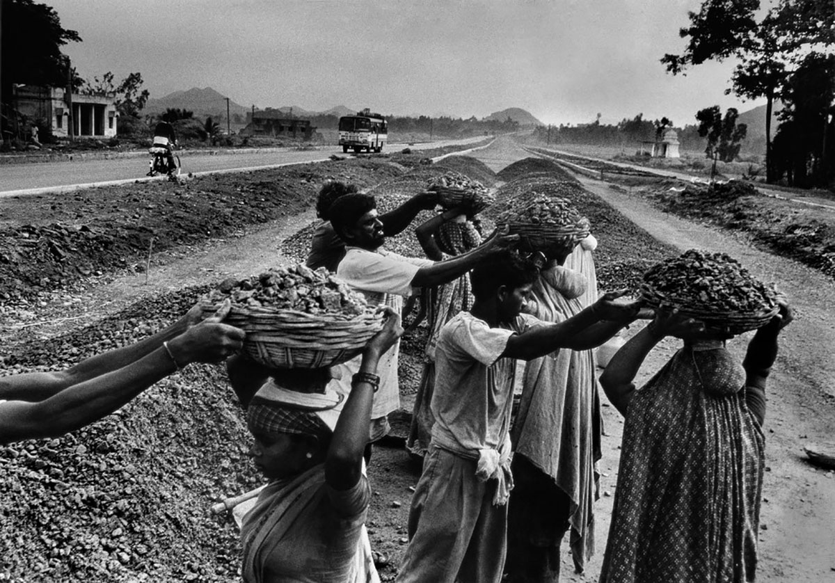 People working in a field holding baskets on their heads