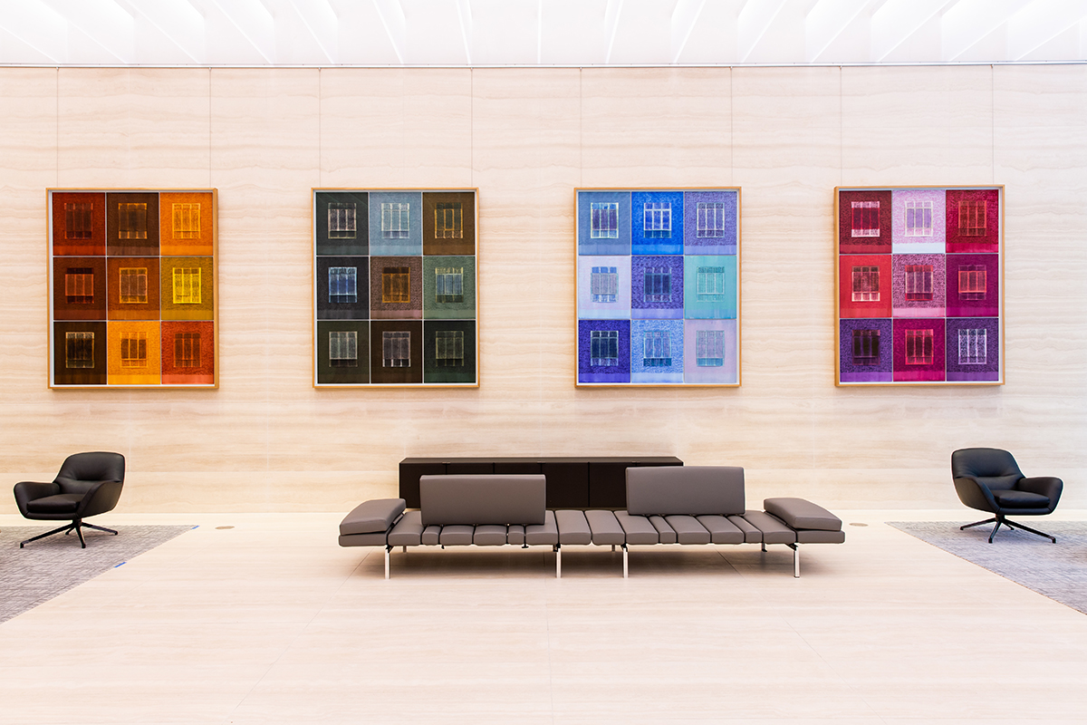 a sofa in a lobby with colourful works of art on the walls behind it 