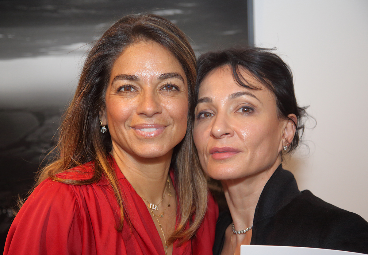 A woman wearing a red top standing next to a woman wearing a black top