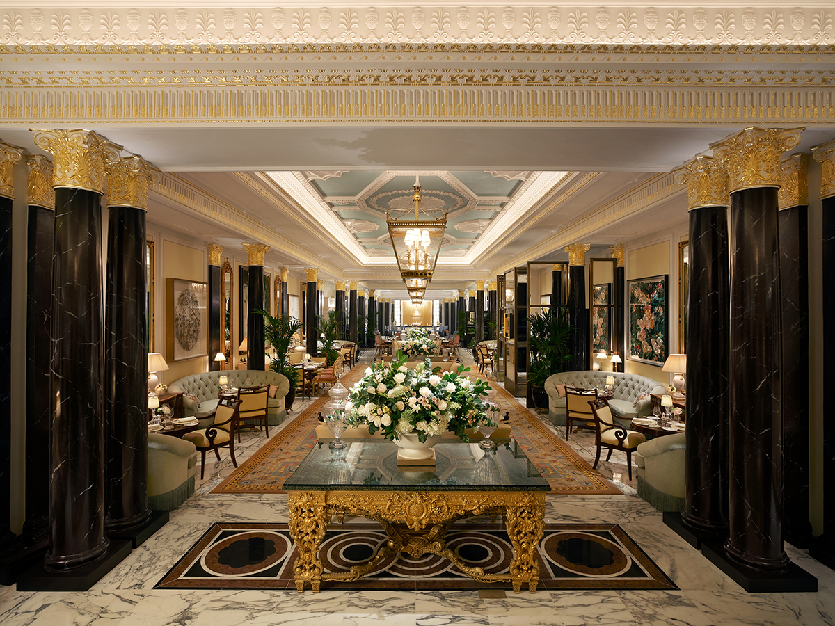 A long sitting room with black and gold pillars and couches with tables