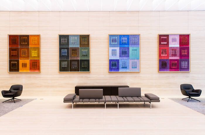 a sofa in a lobby with colourful works of art on the walls behind it