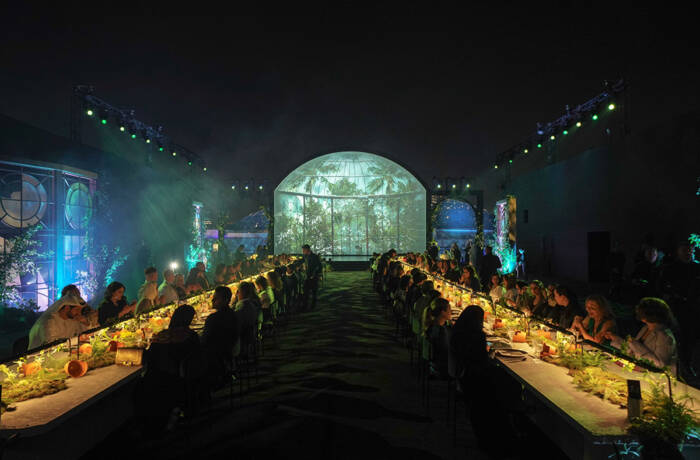 Two long tables in a room with a green light up sign for Richard Mille at the end of the room
