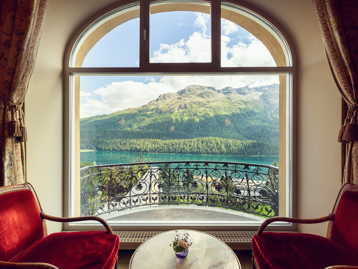 red chairs by a window overlooking a lake and mountain covered in trees