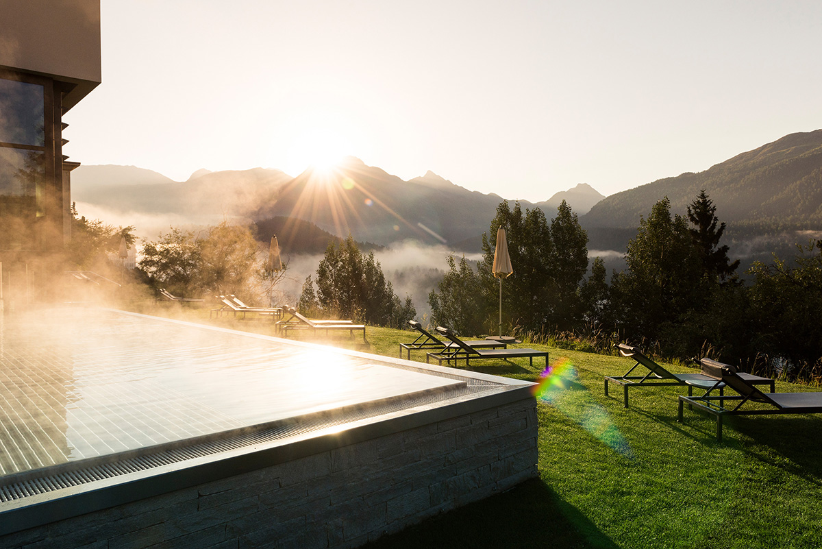 An outdoor pool with steam coming out of it surrounded by grass