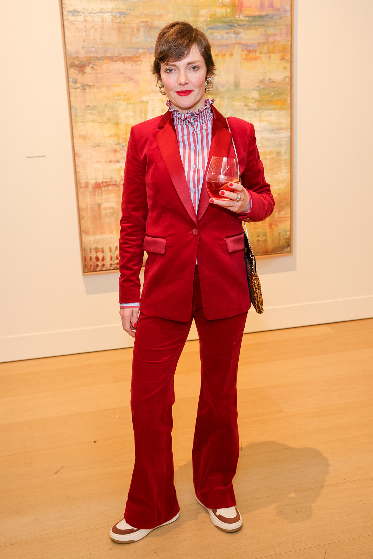 A woman wearing a red suit holding a wine glass