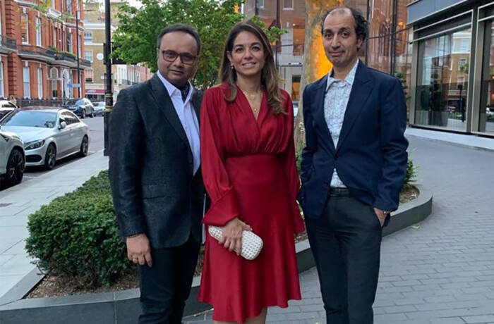 two men standing next to a woman wearing a red dress