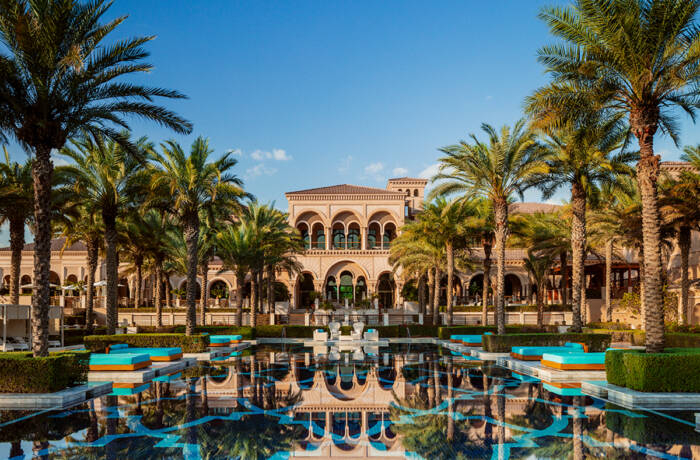 A palace surrounded by palm trees and a swimming pool at the front