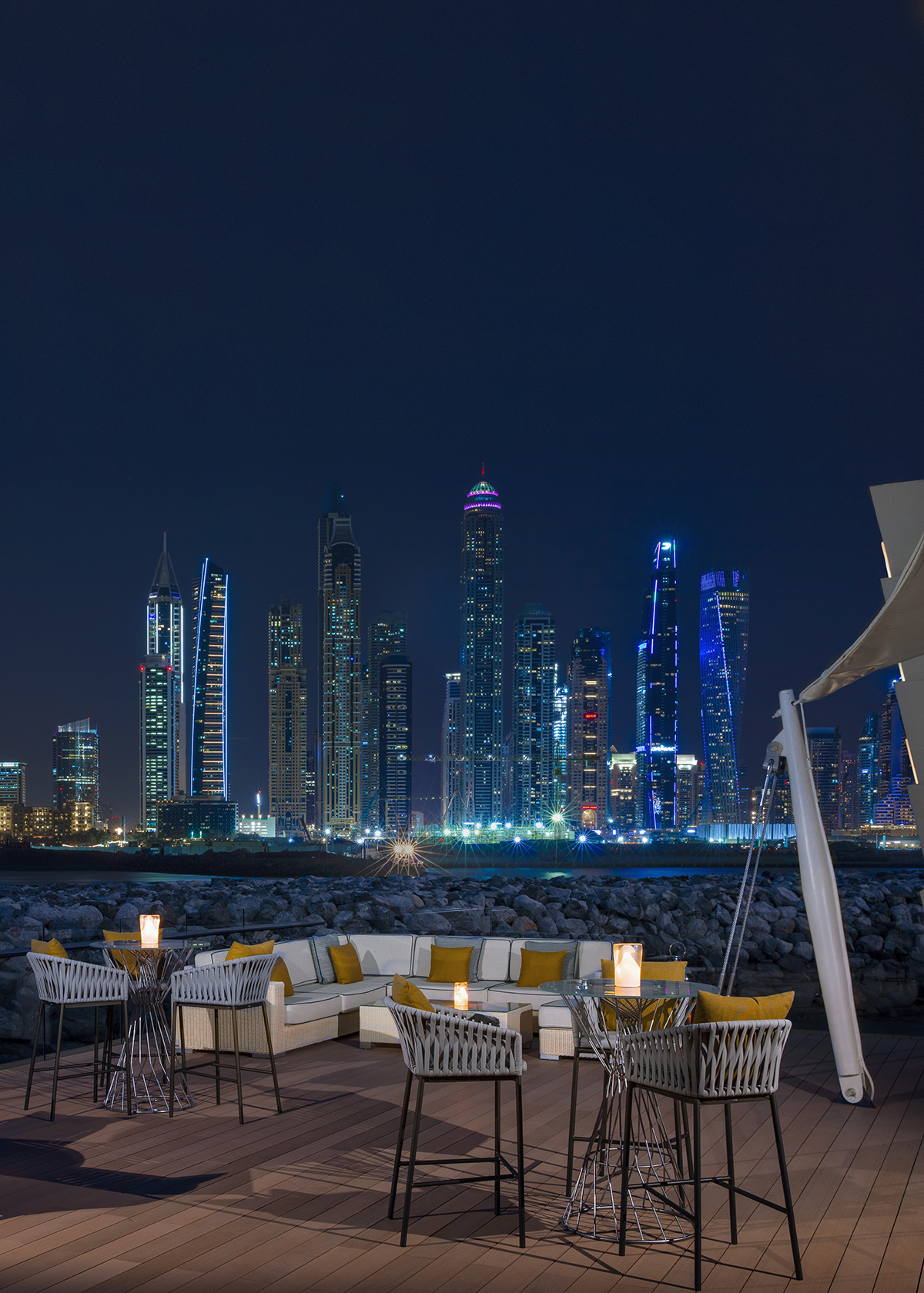 A restaurant with a view of a skyline in Dubai at night with buildings lit up