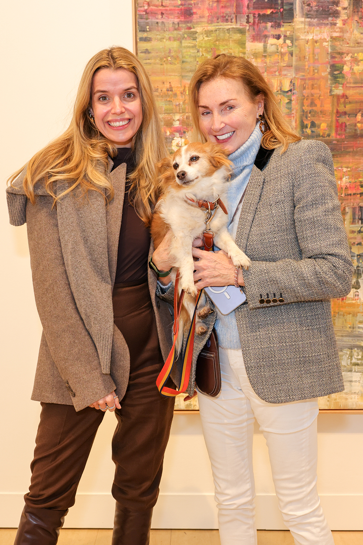 Two women posing for a photo holding a dog
