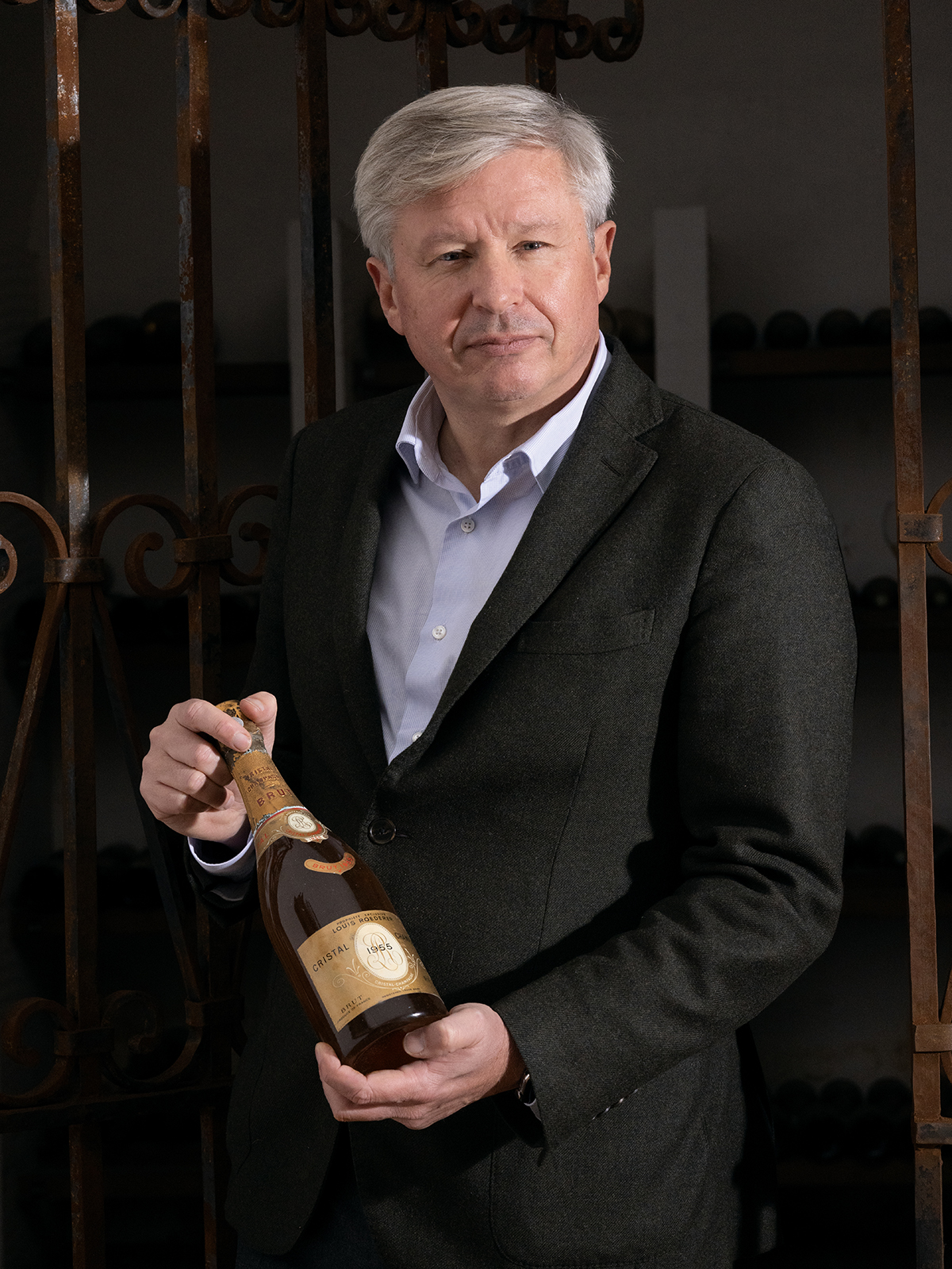 A man wearing a suit holding a bottle of champagne