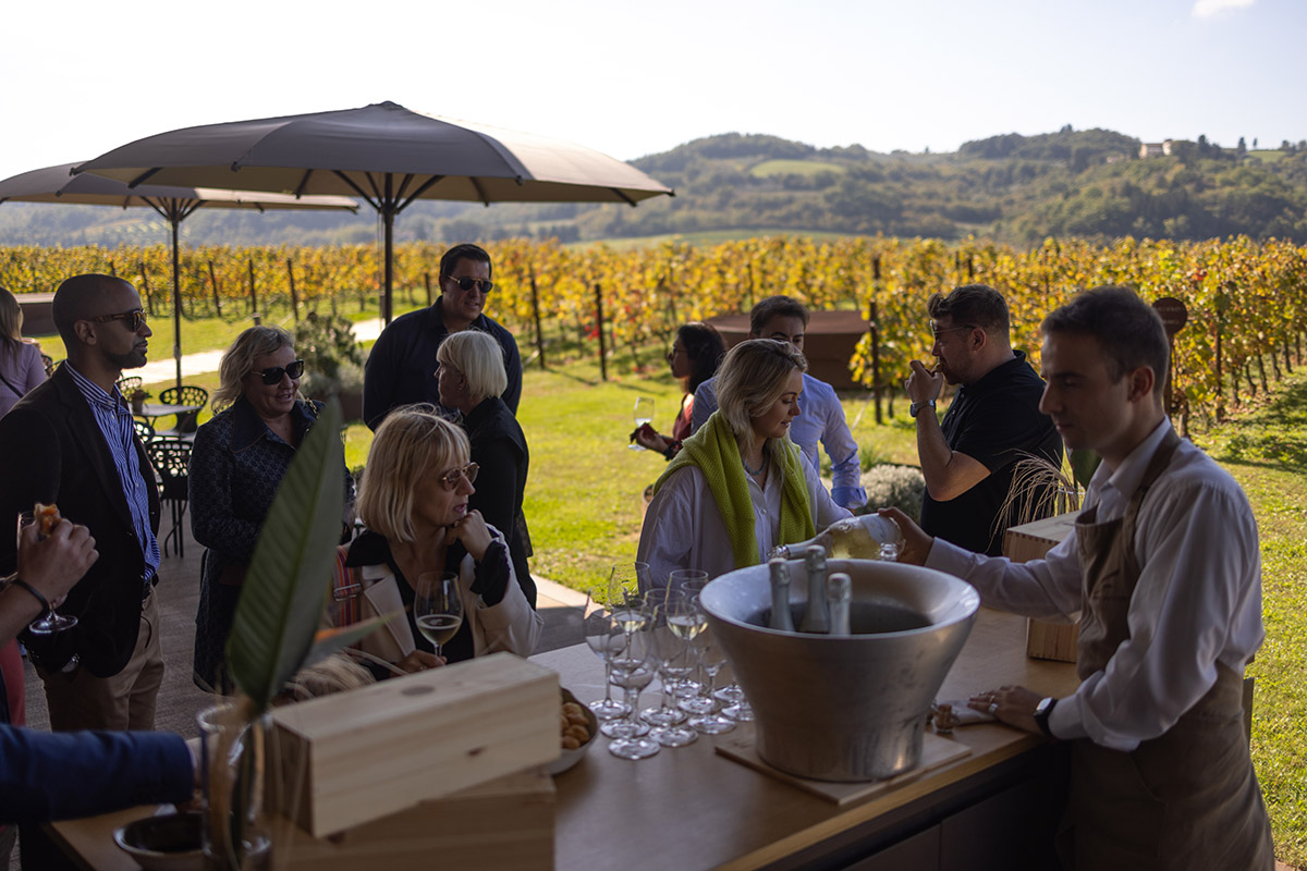 People standing by a bar next to a vineyard