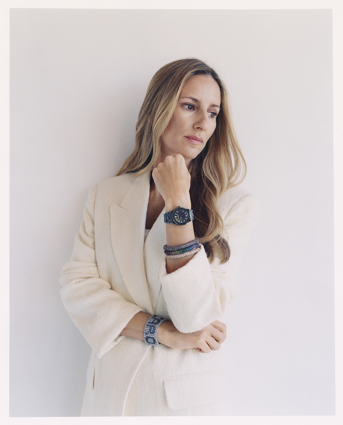 A blonde woman wearing a white jacket and a watch with bracelets