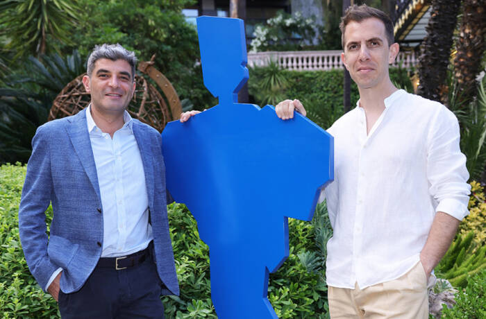 Two men standing next to a blue statue of a person