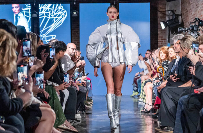 Model in padded silver jacket and matching silver boots walks the runway