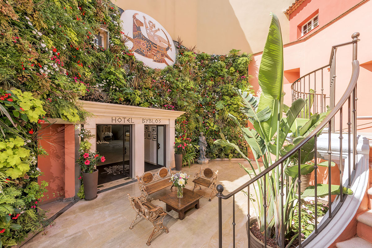 An entrance to a hotel with a mosaic above the door and leaves on the walls