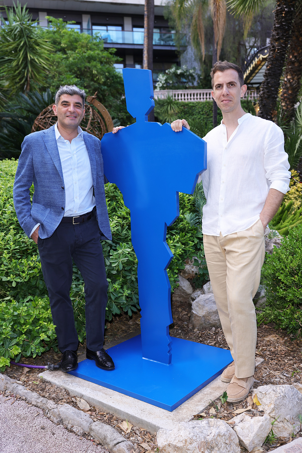 Two men standing next to a blue statue of a person