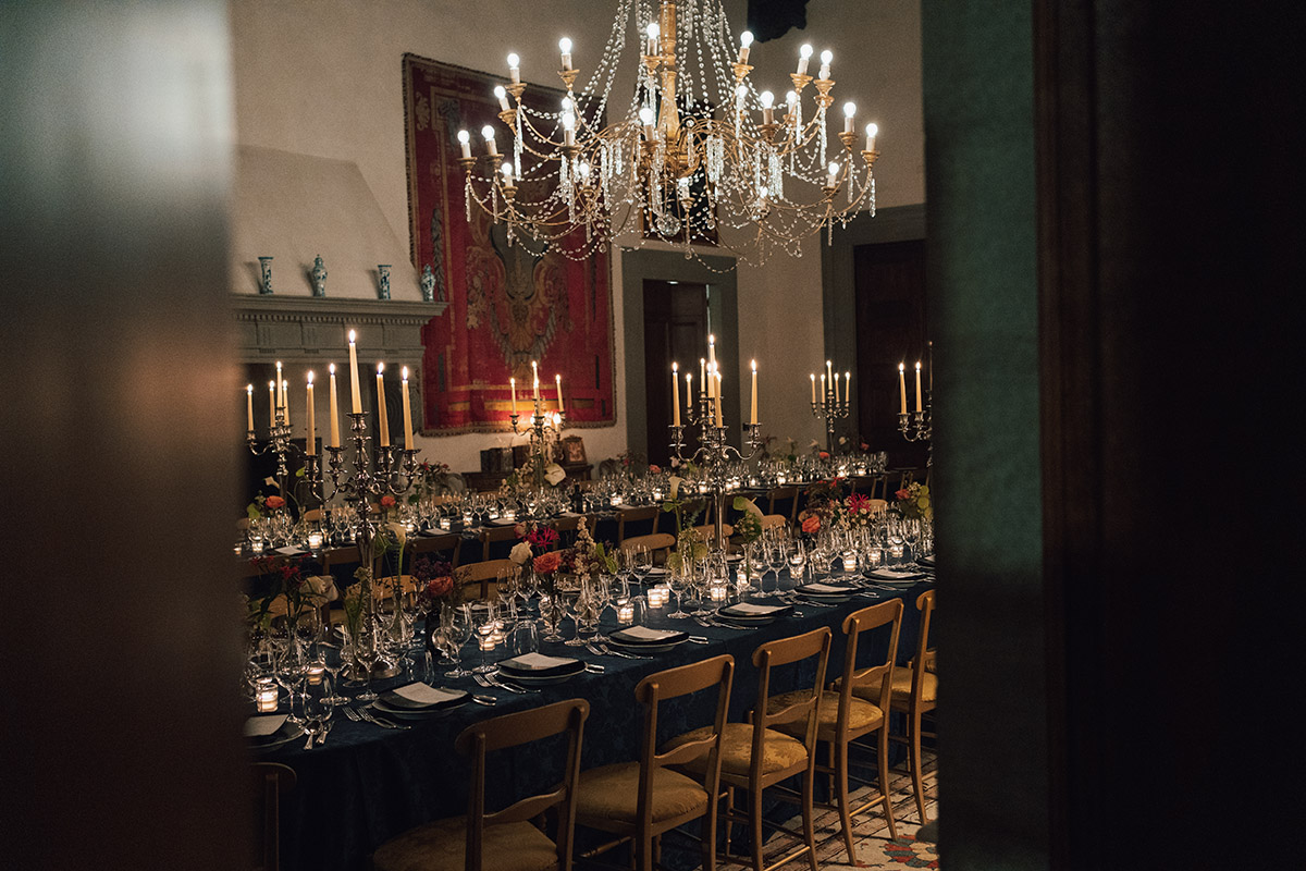 A dinner table with candles and a large chandelier hanging above it