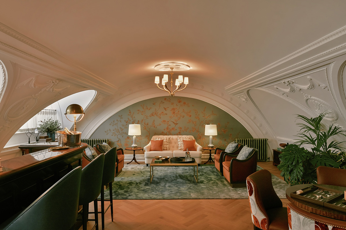 A bar with green bar stools and a cream sofa and red cushions