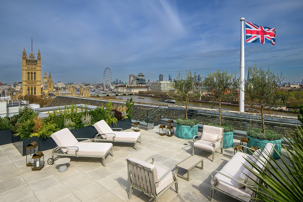 A roof terrace with white bed chairs and tables looking over London