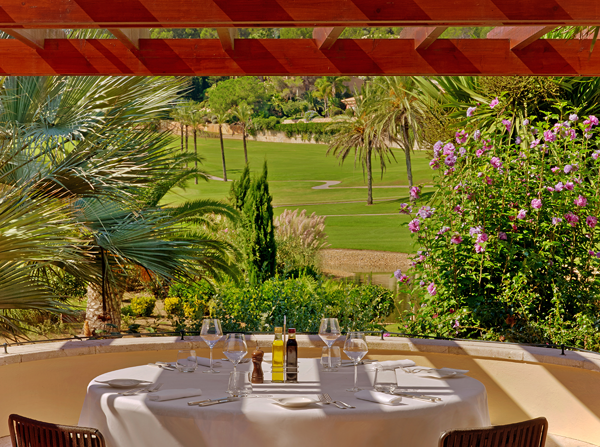 A table looking over a garden with trees and pink flowers