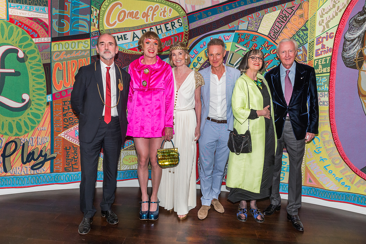 A group of people standing together, one in a bright pink dress and another in bright green