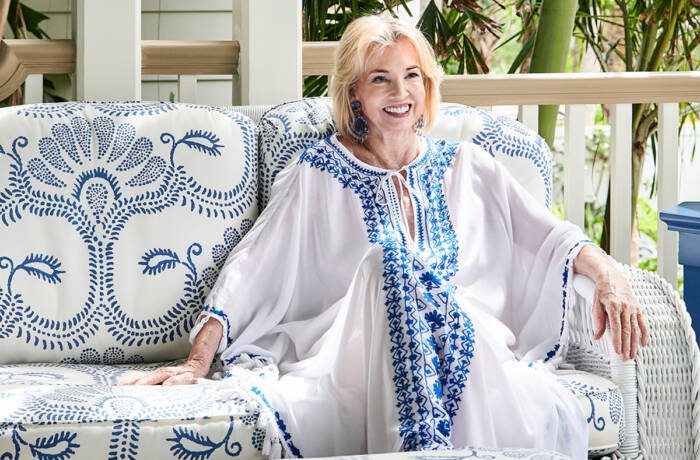 A woman wearing a white and blue dress sitting on a blue and white sofa