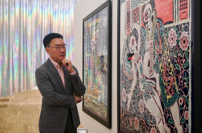 A man in a suit looking at an artwork on the wall