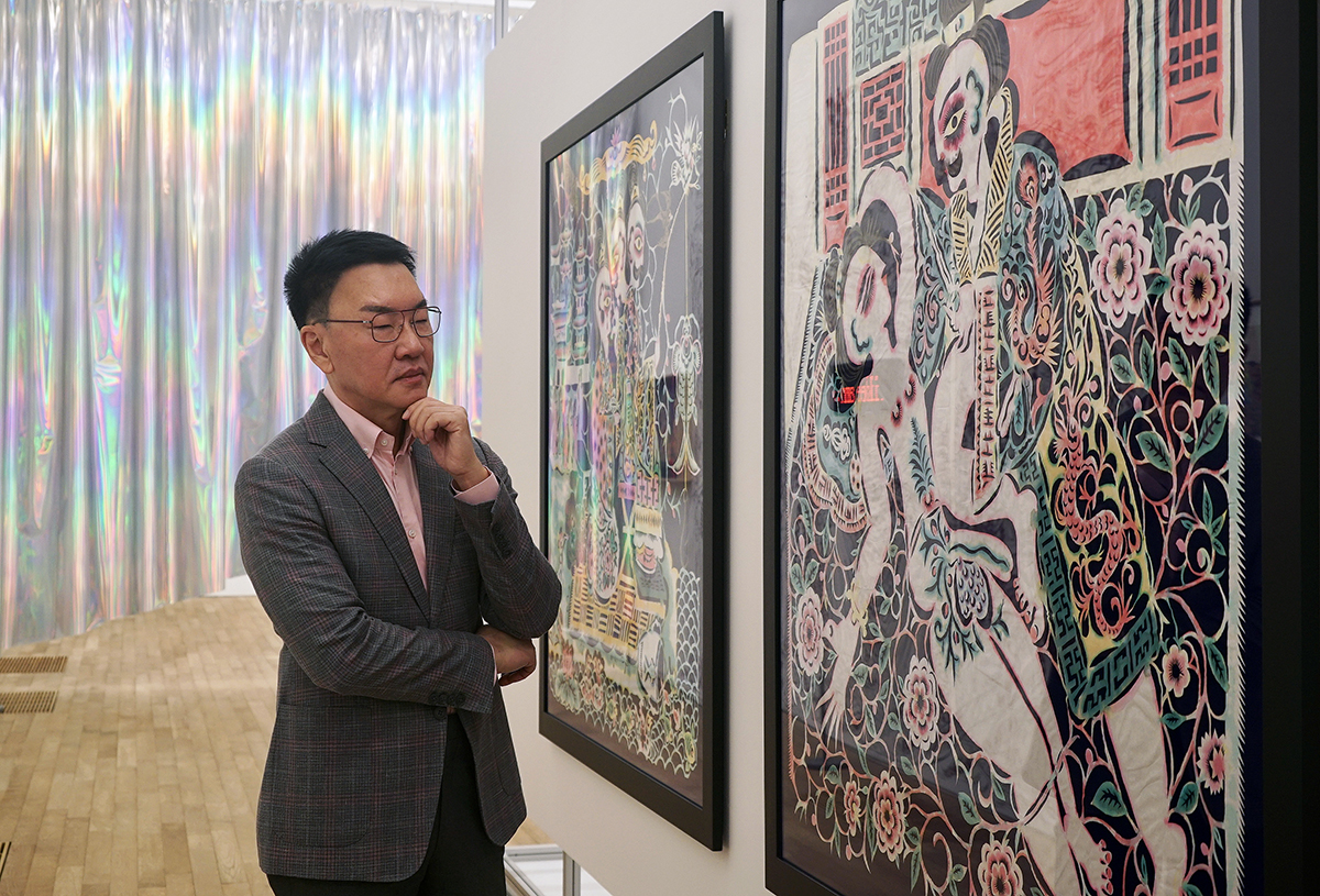 A man in a suit looking at an artwork on the wall