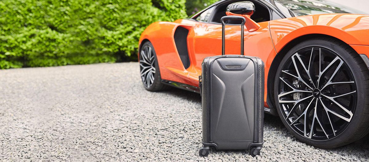 A black suicase next to an orange car