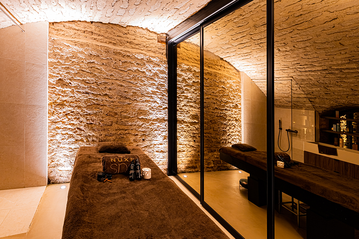 A massage chair with a brown towel on it surrounded by stone and glass walls