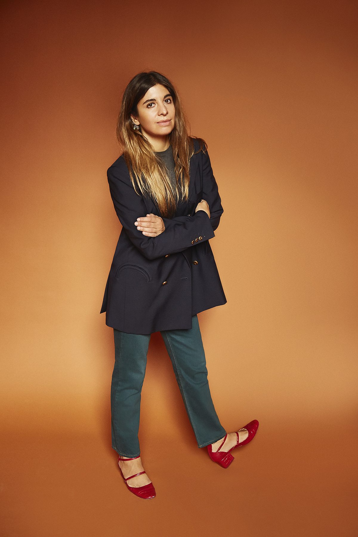 Corrada Rodriguez d'Acri wearing a Blaze blazer and red shows against an orange wall