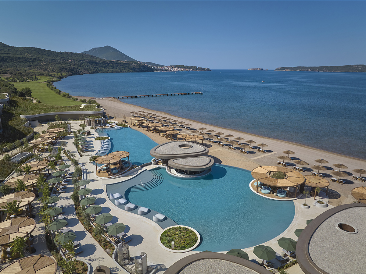 A pool with deckchairs by the sea