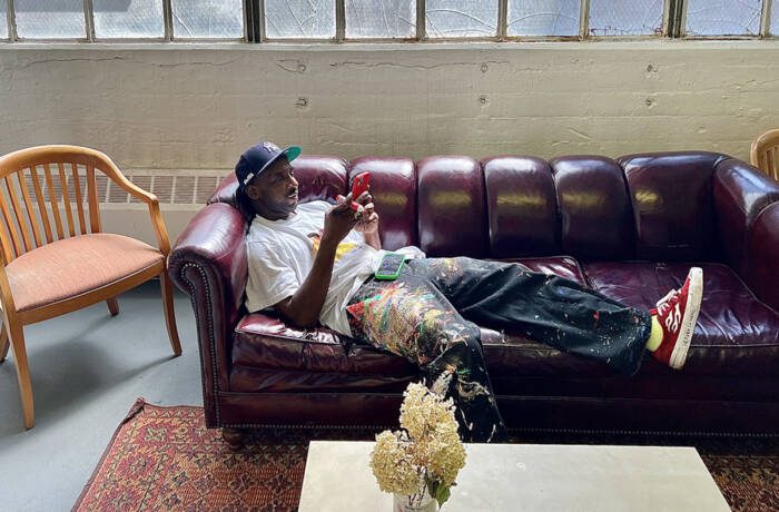 A man with paint on his jeans lying on a purple couch