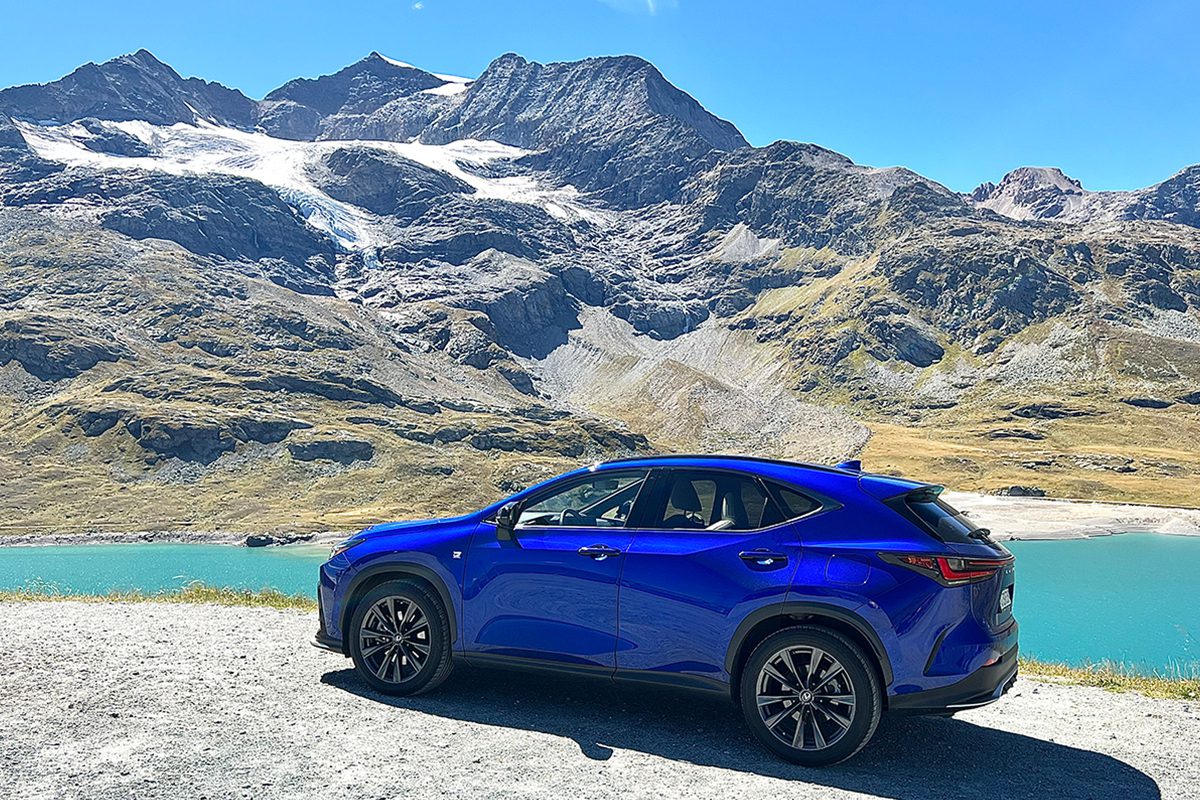 A blue car next to a mountain and lake