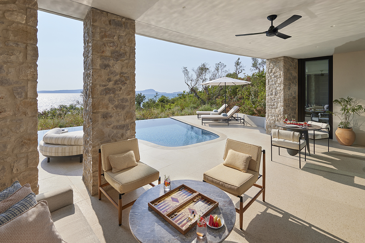 A terrace with beige and wooden chairs and a pool overlooking the sea 