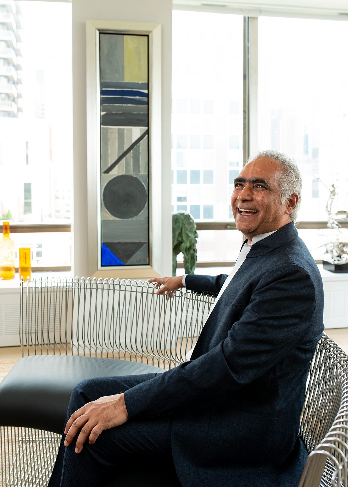 A man sitting on a couch with a mirror and large windows next to him