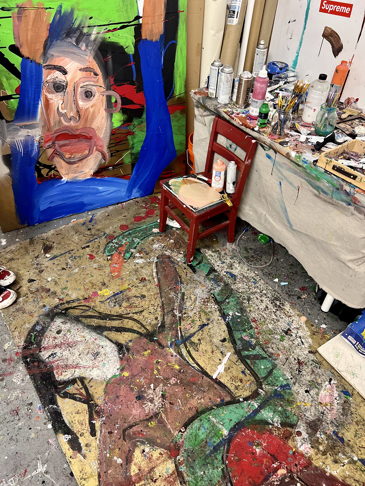 A room with art and paint all of over the floor and chair