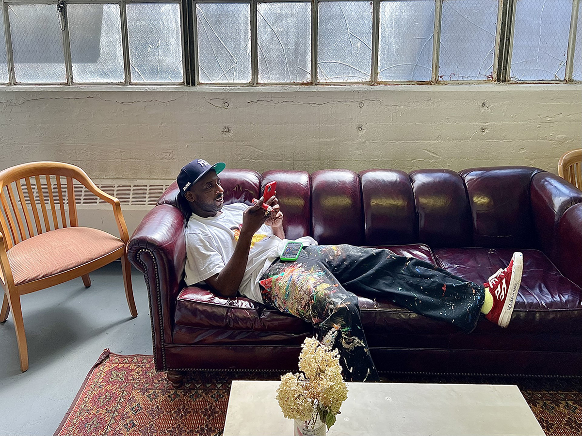 A man with paint on his jeans lying on a purple couch