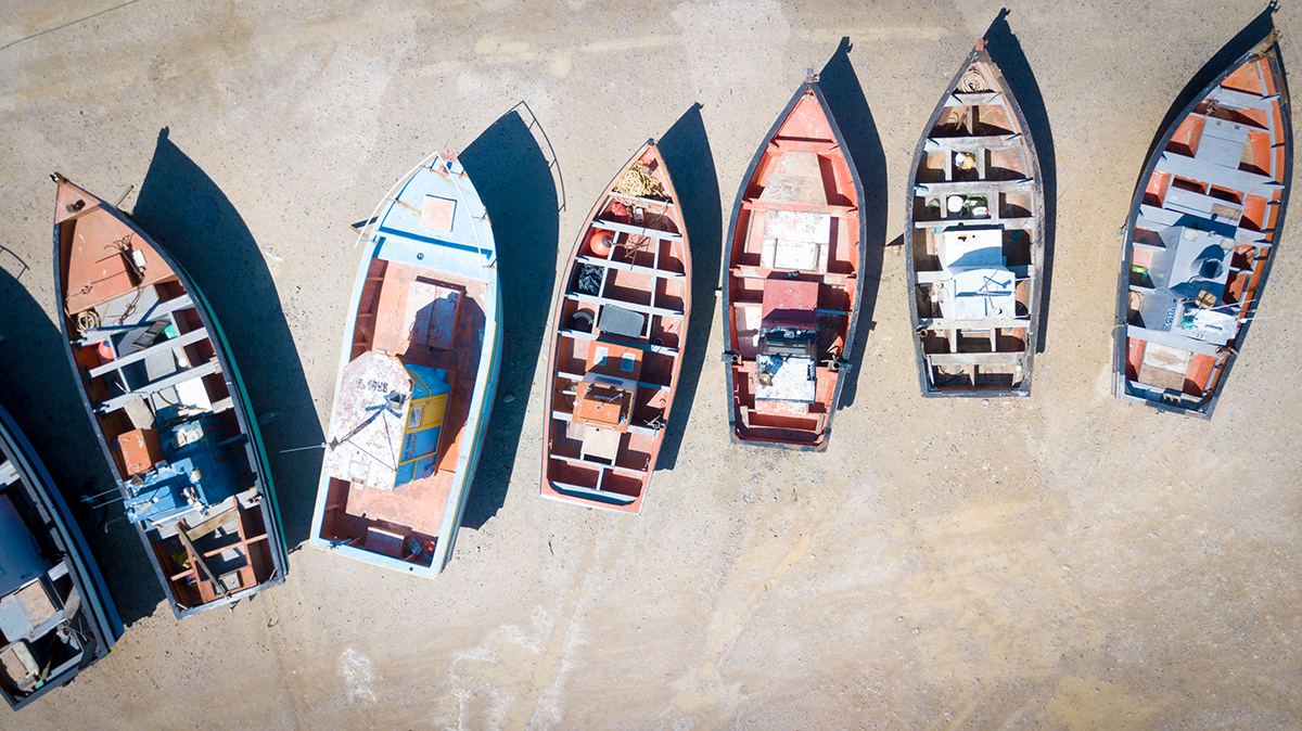 small boats on the sand lined up next to eachother