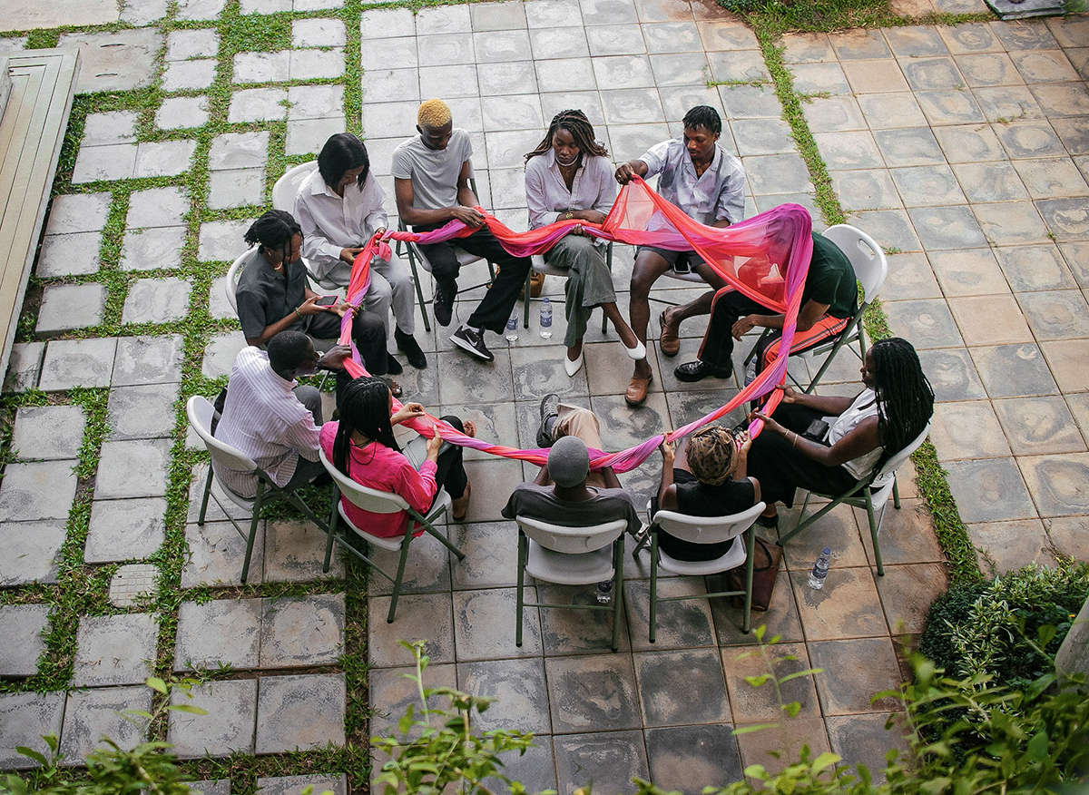 people sitting in a circle holding as pink ribbon