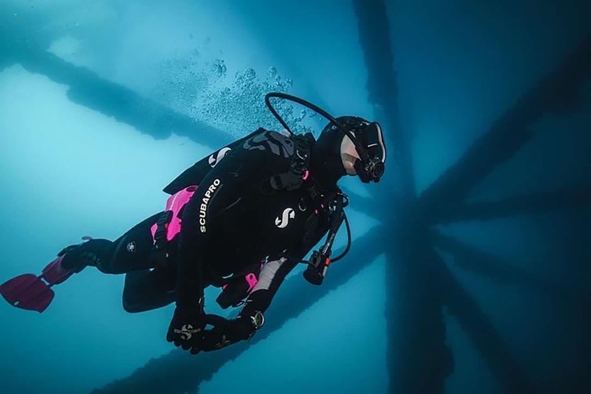 A scubadiver in the ocean surrounded by some metal bars