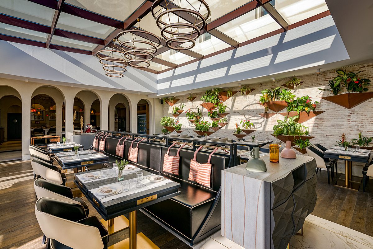 A restaurant with dangling lights and pink cushions on the benches