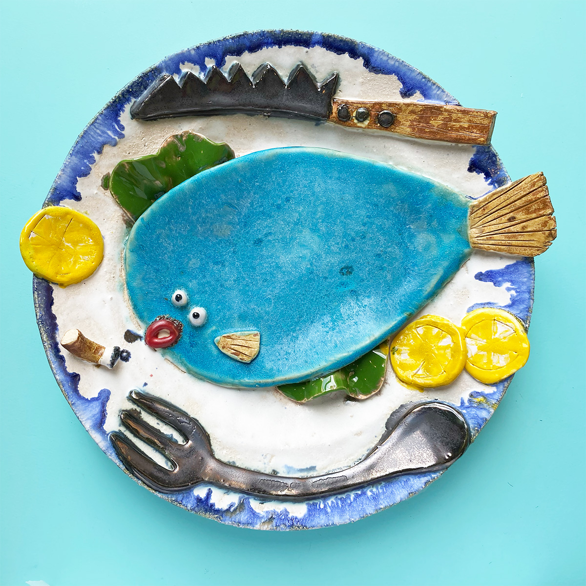 A painted plate with a fish on it and knife and fork 