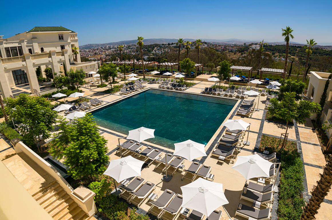 A pool surrounded by grey sun loungers and white umbrellas