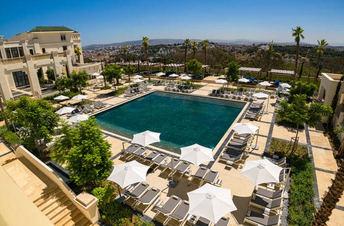 A pool surrounded by grey sun loungers and white umbrellas