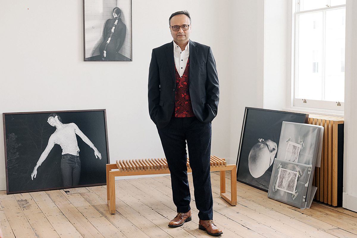 A man in a suit with a red waistcoat standing in a room with art