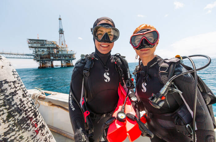 Two women aboard a bot in scuba diving gear