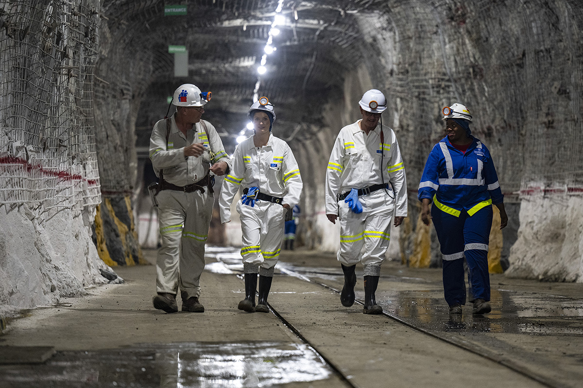 people walking in builder outfits through a mine