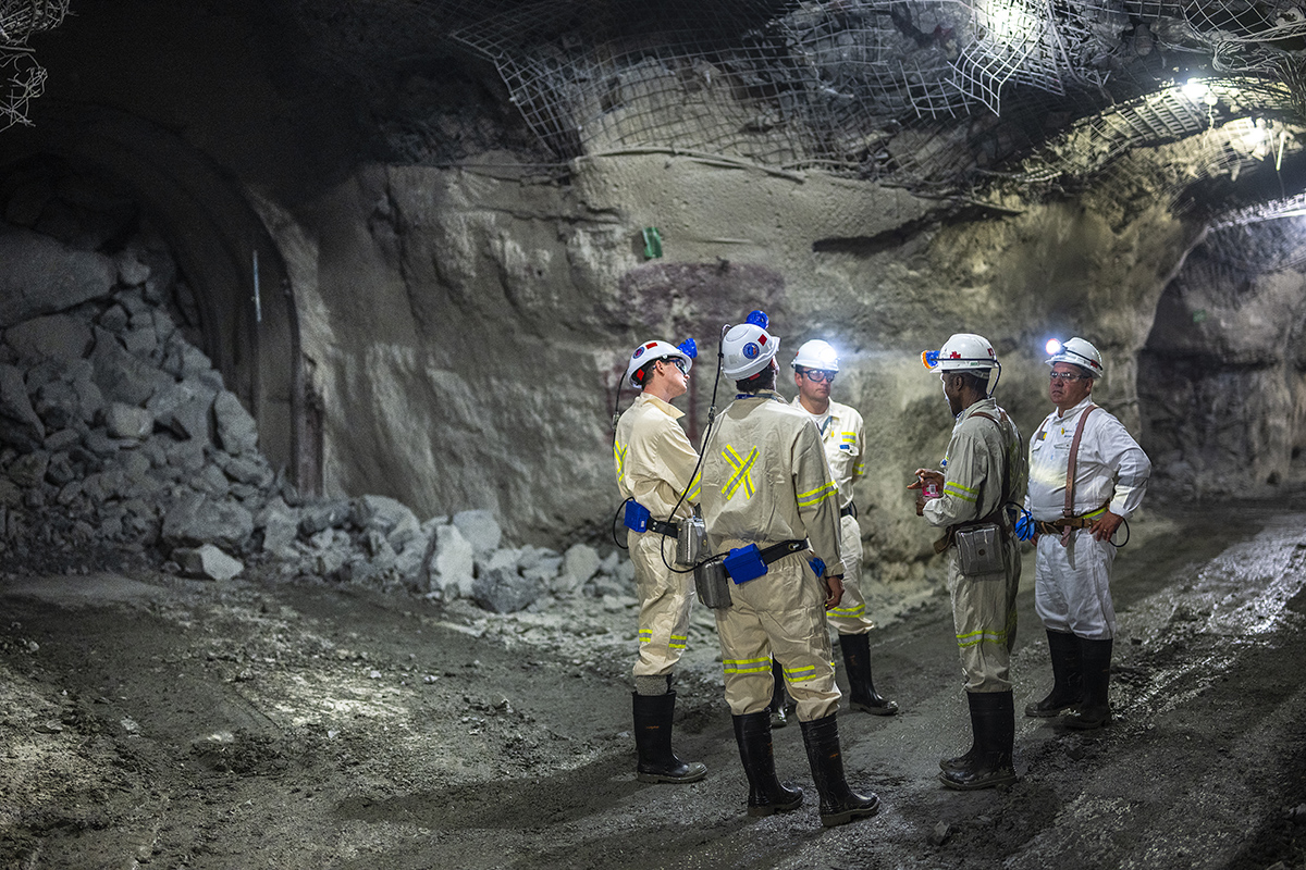 people standing in helmets and white outfits in a mine