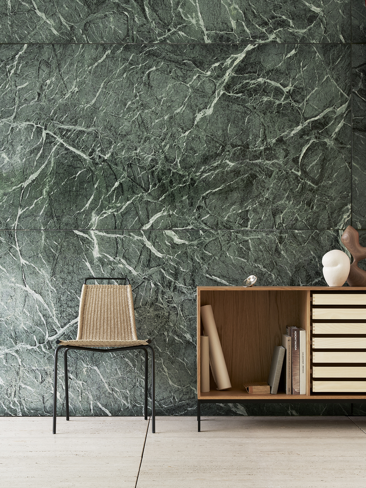 A Carl Hansen chair placed next to a wooden cabinet beside a green marble wall